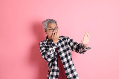 40 'lı yaşlarda Asyalı bir adam pembe arka planda sıradan kıyafetlerle dolanıyor..