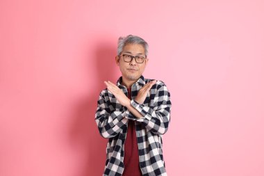 40 'lı yaşlarda Asyalı bir adam pembe arka planda sıradan kıyafetlerle dolanıyor..