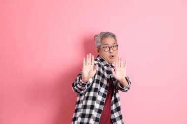 40 'lı yaşlarda Asyalı bir adam pembe arka planda sıradan kıyafetlerle dolanıyor..