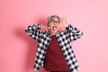 40 'lı yaşlarda Asyalı bir adam pembe arka planda sıradan kıyafetlerle dolanıyor..