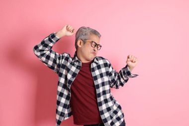 40 'lı yaşlarda Asyalı bir adam pembe arka planda sıradan kıyafetlerle dolanıyor..