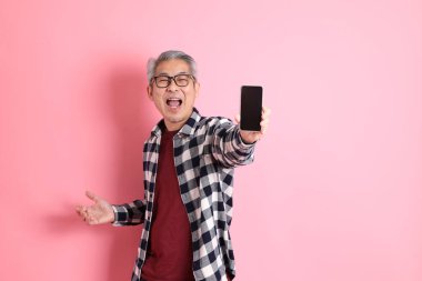 40 'lı yaşlarda Asyalı bir adam pembe arka planda sıradan kıyafetlerle dolanıyor..