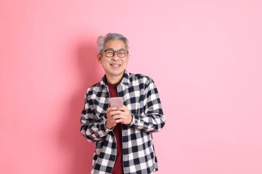 40 'lı yaşlarda Asyalı bir adam pembe arka planda sıradan kıyafetlerle dolanıyor..