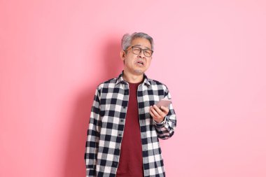 40 'lı yaşlarda Asyalı bir adam pembe arka planda sıradan kıyafetlerle dolanıyor..