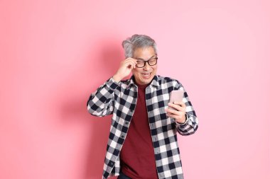 40 'lı yaşlarda Asyalı bir adam pembe arka planda sıradan kıyafetlerle dolanıyor..