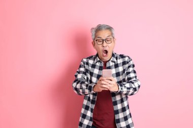 40 'lı yaşlarda Asyalı bir adam pembe arka planda sıradan kıyafetlerle dolanıyor..