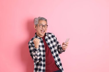 40 'lı yaşlarda Asyalı bir adam pembe arka planda sıradan kıyafetlerle dolanıyor..