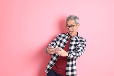 40 'lı yaşlarda Asyalı bir adam pembe arka planda sıradan kıyafetlerle dolanıyor..