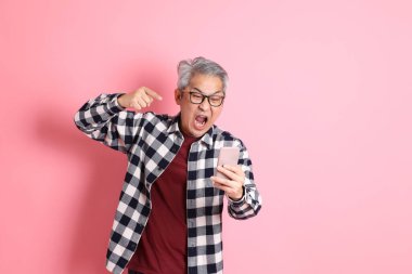 40 'lı yaşlarda Asyalı bir adam pembe arka planda sıradan kıyafetlerle dolanıyor..