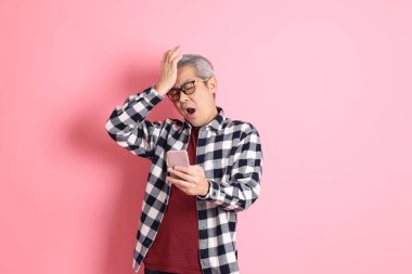 40 'lı yaşlarda Asyalı bir adam pembe arka planda sıradan kıyafetlerle dolanıyor..