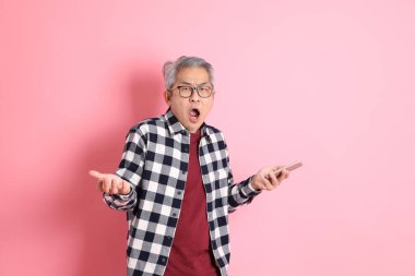 40 'lı yaşlarda Asyalı bir adam pembe arka planda sıradan kıyafetlerle dolanıyor..