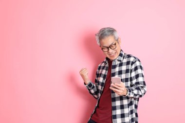 40 'lı yaşlarda Asyalı bir adam pembe arka planda sıradan kıyafetlerle dolanıyor..