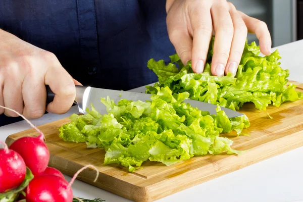 Young woman making salad in kitchen — Stock Photo, Image