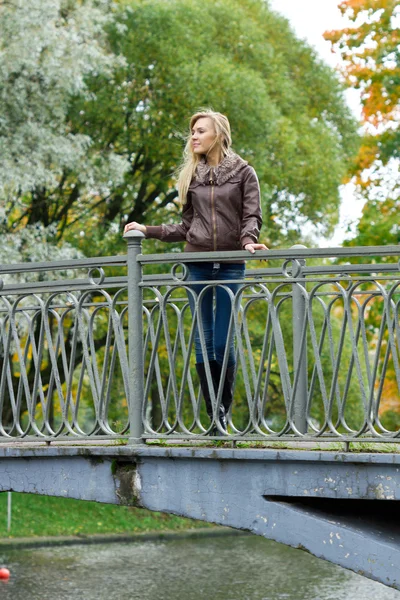 Ung blond kvinna på en bro i parken — Stockfoto