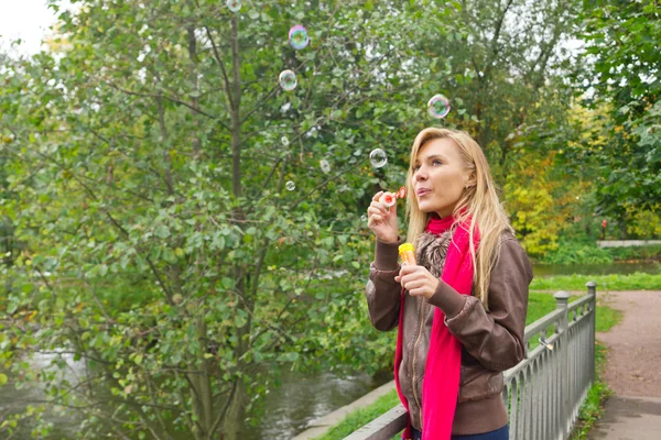 Giovane donna bionda che soffia bolle di sapone nel parco — Foto Stock