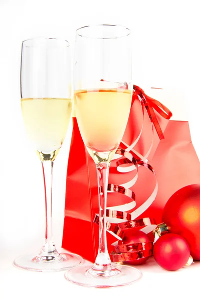 Dos copas de cristal con champán, bolas de Navidad y presente sobre fondo blanco — Foto de Stock