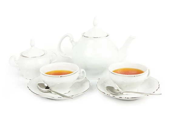 Чашки чая, чайник и сахар на белом — стоковое фото