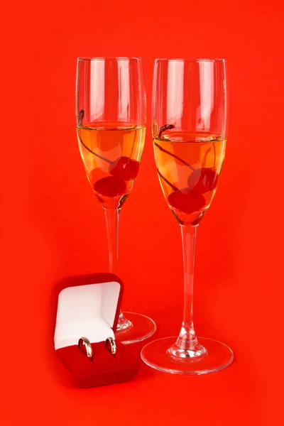 Two glass goblets with champagne and wedding rings — Stock Photo, Image