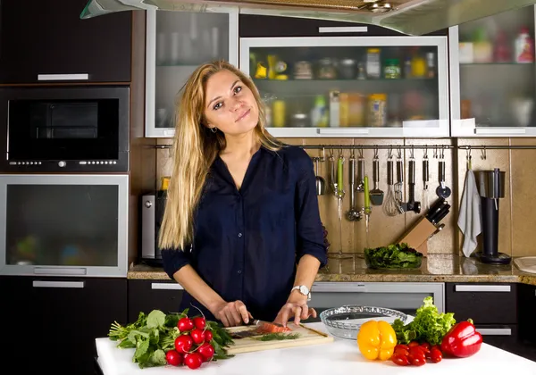 Jonge mooie vrouw salade in de keuken koken — Stockfoto