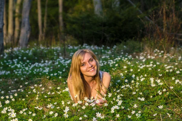 Mladá hezká blondýnka na louce s květinami — Stock fotografie