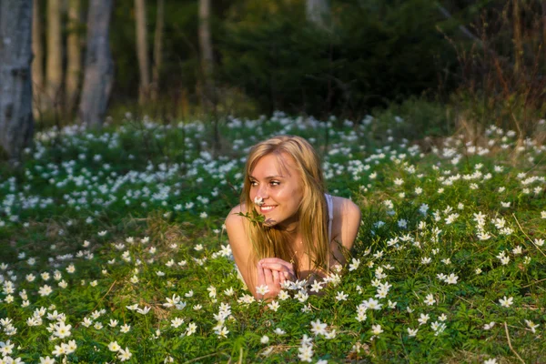 Mladá hezká blondýnka na louce s květinami — Stock fotografie