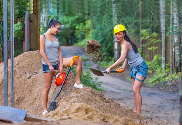 Pretty young woman builder digging a shovel — Stock Photo, Image