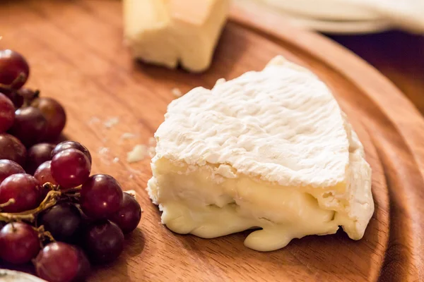 与葡萄的木制板上的奶酪 — 图库照片