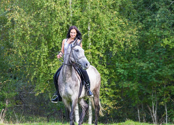 Elegante aantrekkelijke vrouw rijden een paard weide — Stockfoto