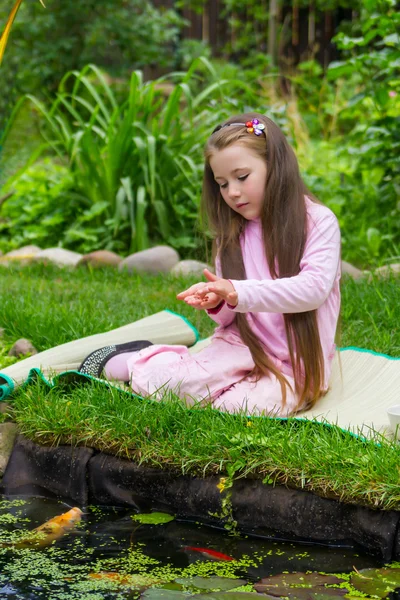 Petite fille nourrissant des poissons — Photo