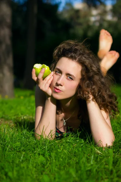 Beautiful young woman eating apple outdoors — Stock Photo, Image