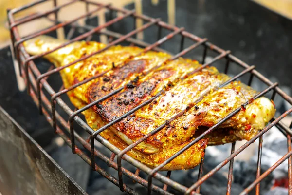 Grilled fish fried with lemon, citrus and spices, pepper. Exotic dietary marine fish. Dorado and perch in a restaurant recipe. Fish steak, barbecue, picnic. Fish cooked on fire coal on grill.