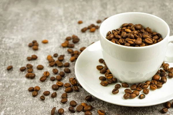 White coffee cup with roasted coffee beans on gray concrete backgfound with copy space. — Stock fotografie