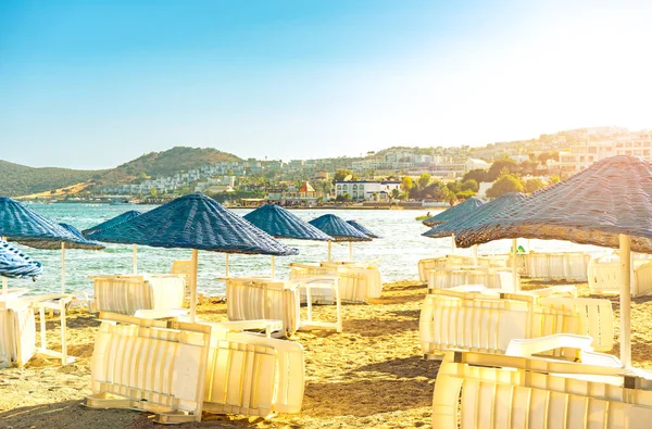 Empty beach loungers without people in quarantine of pandemic, start or the end of summer vacation season . Umbrella on a sunbed near the sea and ocean on vacation with travel and tourism. Hotel, touristic, travel, resort concept