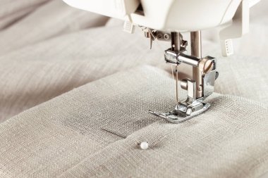 Modern sewing machine presser foot with linen fabric and thread, closeup, copy space. Sewing process clothes, curtains, upholstery. Business, hobby, handmade, zero waste, recycling, repair concept