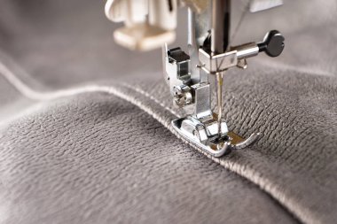 Modern sewing machine presser foot with linen fabric and thread, closeup, copy space. Sewing process clothes, curtains, upholstery. Business, hobby, handmade, zero waste recycling, repair concept, DIY