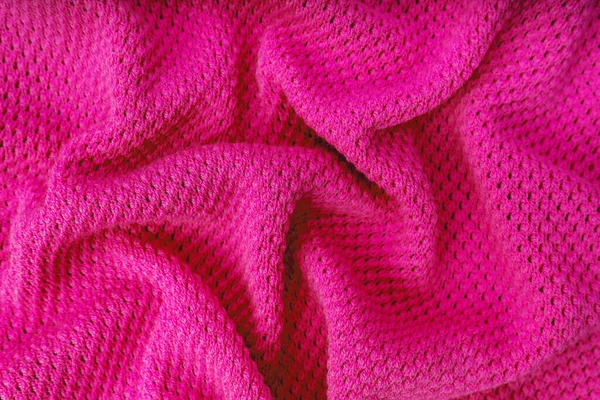 Close up background of knitted wool fabric with dots pattern. Bright pink color crumpled knitting wool knitwear texture. Openwork abstract knitted jersey fabric abstract backdrop