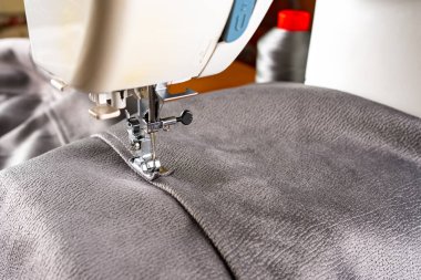 Modern sewing machine presser foot with gray fabric and thread, closeup, copy space. Sewing process clothes, curtains, upholstery. Business, hobby, handmade, zero waste recycling, repair concept, DIY