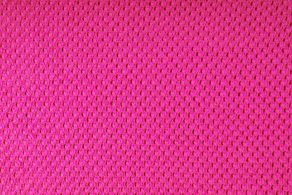 Close up background of knitted wool fabric with dots pattern. Bright pink color wool knitwear texture. Openwork abstract knitted jersey. Fabric abstract backdrop