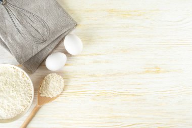 Baking cooking Ingredients background with copy space. Flour, eggs and whisk on white wooden surface. Top view, flat lay. Mockup menu, banner, header for site, baking concept