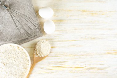 Baking cooking Ingredients background with copy space. Flour, eggs and whisk on white wooden surface. Top view, flat lay. Mockup menu, banner, header for site, baking concept