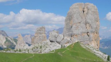 Dolomite dağlarının bir kısmının panoramik görüntüsü. Bazı kaya kuleleri yeşil bir çayırda ve mavi bir gökyüzünde duruyor. panoramik kamera hareketi