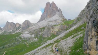 Genç bir çift yüksek bir dağ yolunda yürüyor. Spor yapıyorlar ama teknik ekipmanları yok. Etrafları çıplak kaya tepeleriyle çevrili. Arka planda bir zirvede bir barınak göze çarpıyor.