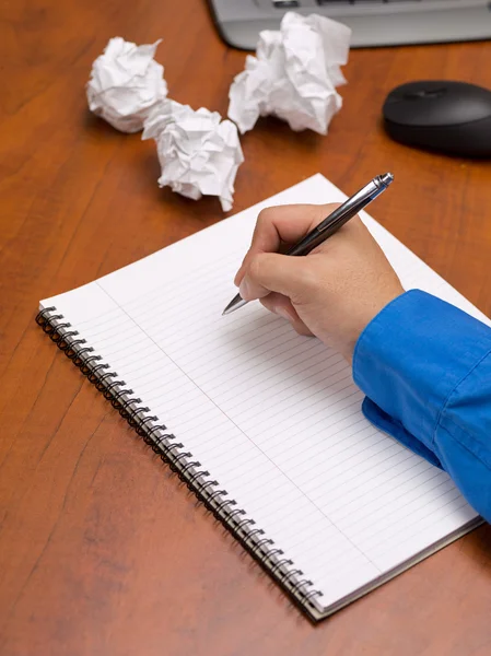 Close up shot of a person writing on spiral notepad on desk — Stock Photo, Image