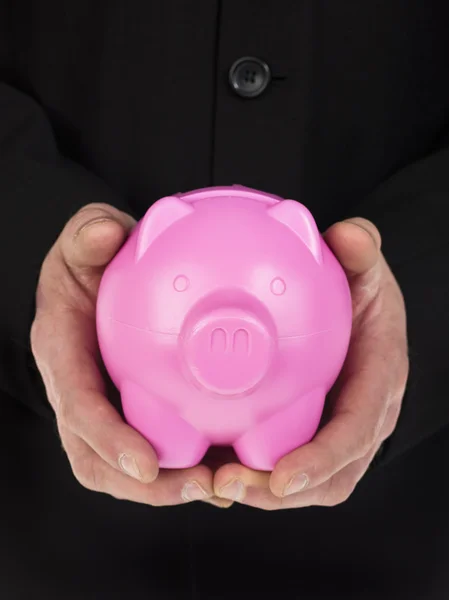 Mans mão segurando um banco piggy rosa — Fotografia de Stock