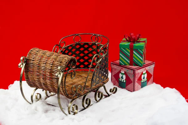 Geschenke auf dem Schnee neben Korbschlitten — Stockfoto