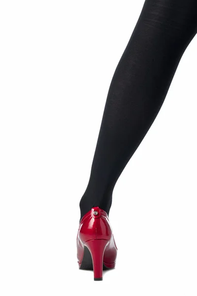 Kvinnliga benet med svart strumpa och röda skor — Stockfoto