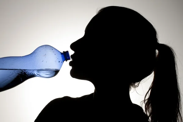 Девушка пьет воду из голубой бутылки — стоковое фото