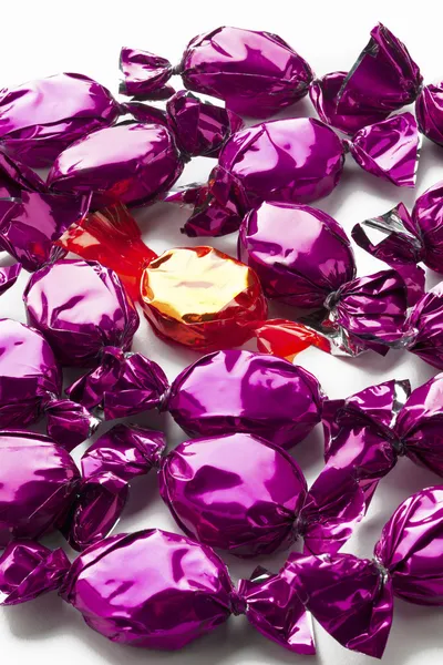 Gouden hard candy geregeld tussen paarse harde snoepjes — Stockfoto