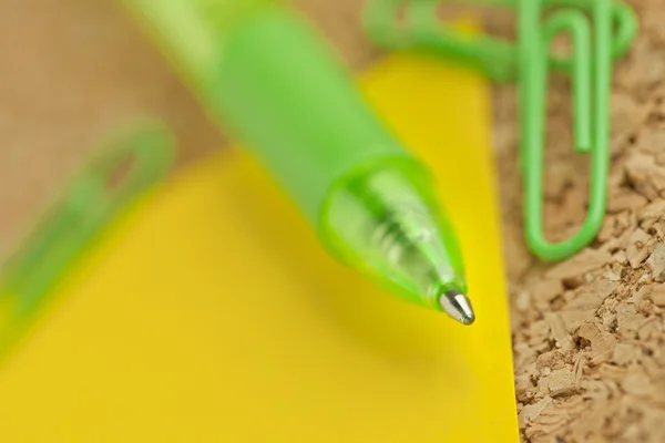 Penna a sfera verde con carta gialla e graffetta — Foto Stock