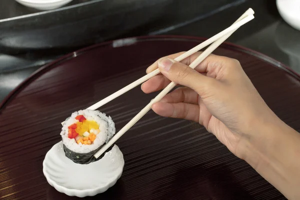 Hand houden sushi met eetstokjes — Stockfoto